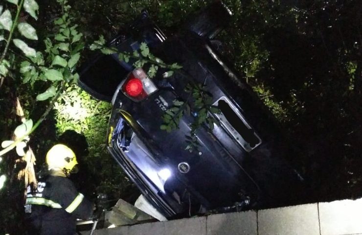 Carro cai em ribanceira, fica preso em árvore e quase atinge casa