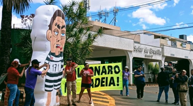 Manifestantes inflam boneco de Bolsonaro vestido de presidiário em frente a condomínio