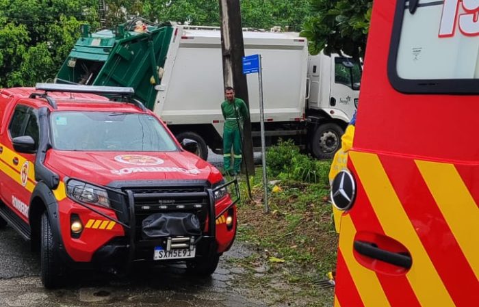 Caminhão de coleta prensa gari contra poste durante manobra