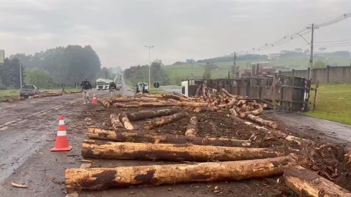 Carreta tomba, toras atingem carro e motorista foge na BR-282